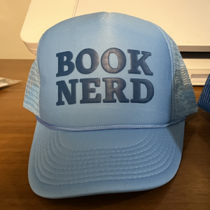 sky blue hat with "BOOK NERD" in navy letters